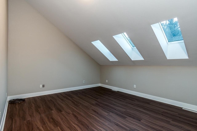 additional living space with lofted ceiling with skylight and dark hardwood / wood-style flooring