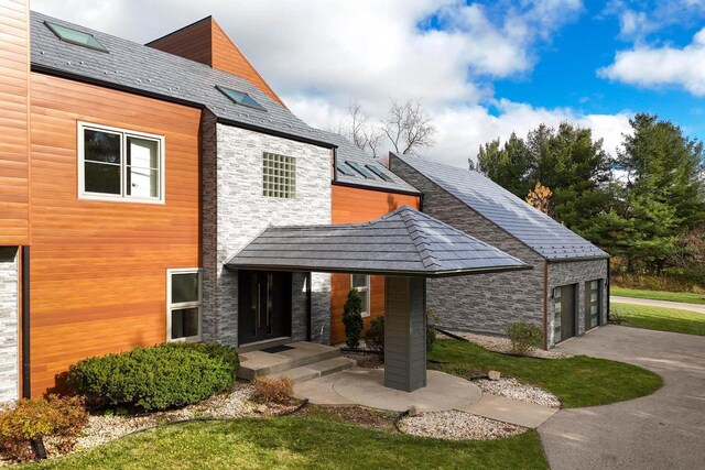 4720 Sumac Rd, Middleton, WI 53562 - view of property exterior with a high end roof, stone siding, a garage, driveway, and a lawn