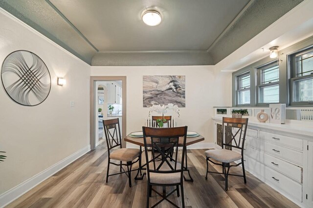 dining room featuring wood-type flooring, ornamental molding, and a textured ceiling