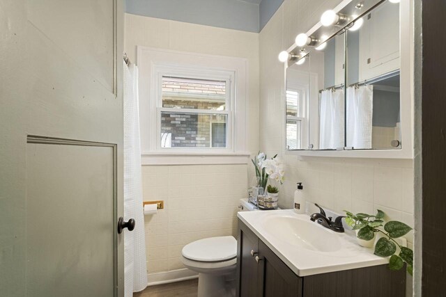 bathroom featuring tile walls, hardwood / wood-style floors, vanity, and toilet