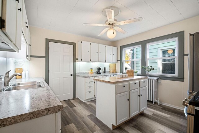 kitchen with white cabinetry, sink, radiator, a center island, and dark hardwood / wood-style flooring