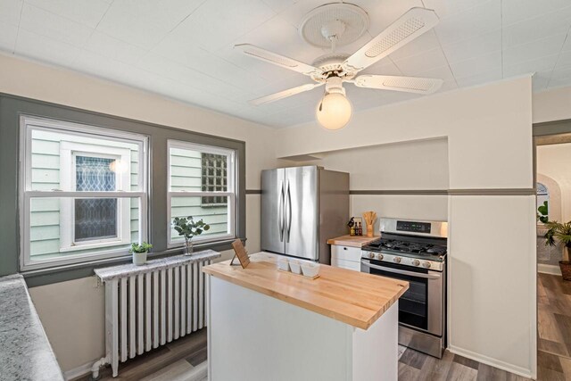 kitchen featuring stainless steel appliances, radiator, butcher block counters, and a wealth of natural light