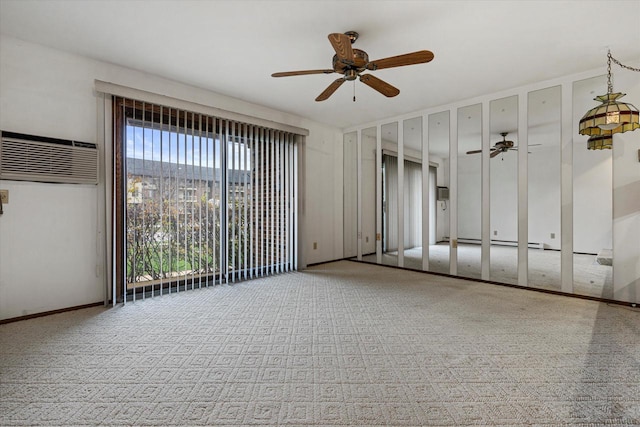 spare room with carpet floors, a baseboard radiator, a wall mounted AC, and ceiling fan