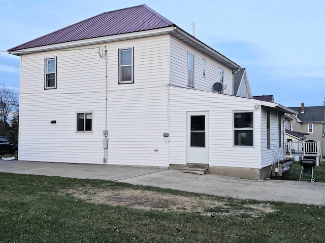 back of house with a patio and a lawn