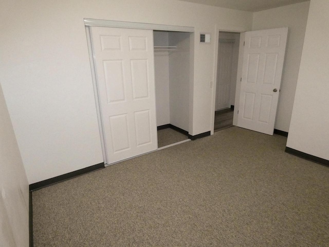 unfurnished bedroom featuring dark carpet and a closet