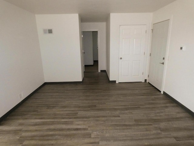 unfurnished room with dark wood-type flooring