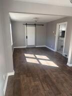 unfurnished living room featuring a barn door and dark hardwood / wood-style floors