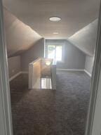 bonus room featuring dark colored carpet and lofted ceiling