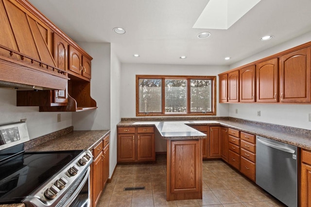 kitchen featuring a skylight, appliances with stainless steel finishes, light tile patterned flooring, custom range hood, and a center island