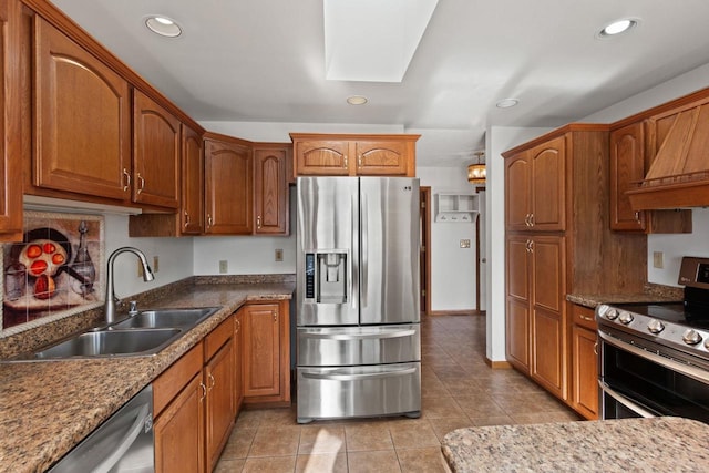 kitchen featuring light tile patterned floors, stainless steel appliances, light stone counters, and sink