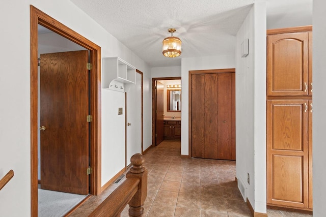 hallway featuring a textured ceiling and a chandelier