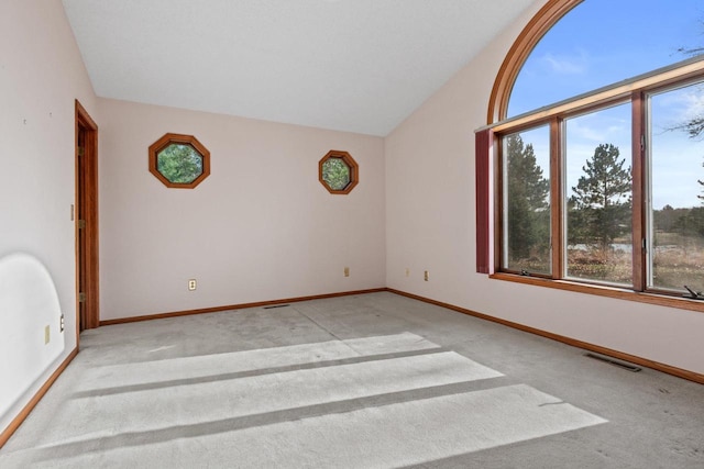 carpeted empty room with lofted ceiling