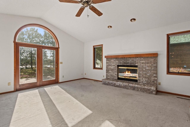 unfurnished living room with a brick fireplace, light carpet, lofted ceiling, and ceiling fan