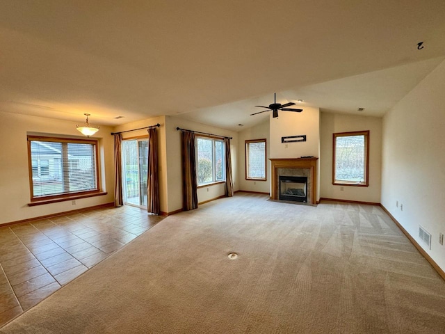 unfurnished living room featuring a tile fireplace, ceiling fan, light carpet, and vaulted ceiling