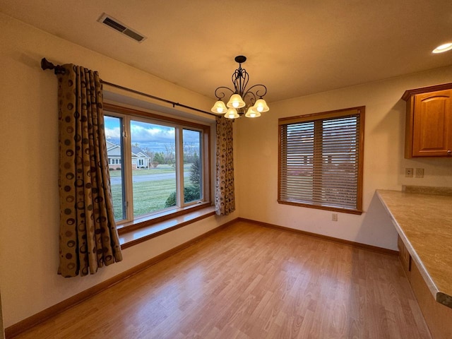 unfurnished dining area with light hardwood / wood-style floors and a notable chandelier