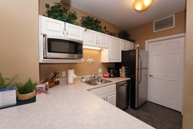 kitchen featuring white cabinetry, sink, stainless steel appliances, and dark tile patterned flooring