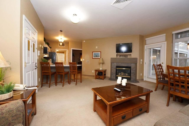 living room featuring light colored carpet and a tiled fireplace