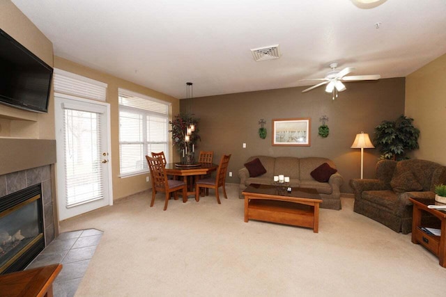 carpeted living room with ceiling fan and a tile fireplace