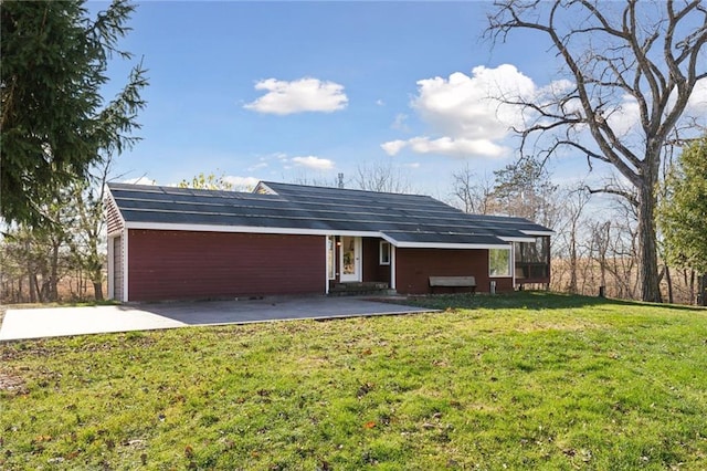 rear view of house featuring solar panels and a yard