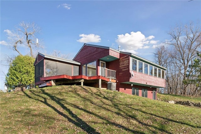 rear view of house with a lawn and a sunroom