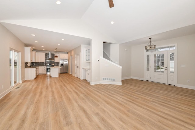 unfurnished living room with light hardwood / wood-style flooring, a chandelier, and vaulted ceiling