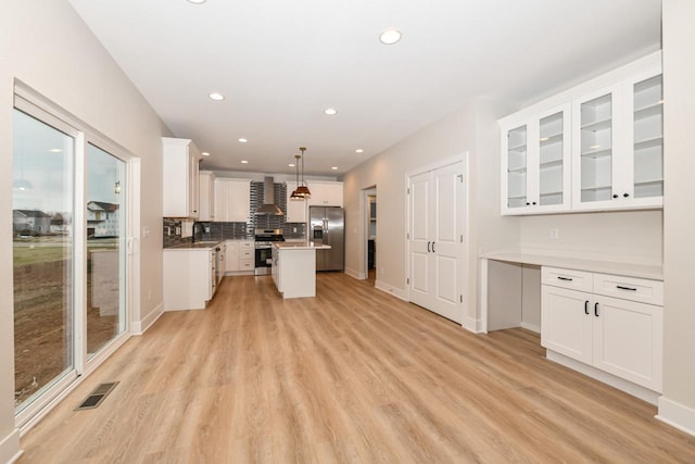 kitchen featuring white cabinets, decorative light fixtures, a center island, and appliances with stainless steel finishes