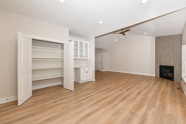 unfurnished living room featuring ceiling fan, a fireplace, lofted ceiling, and light wood-type flooring