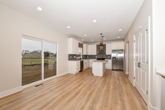 kitchen with pendant lighting, a kitchen island, white cabinets, and stainless steel appliances