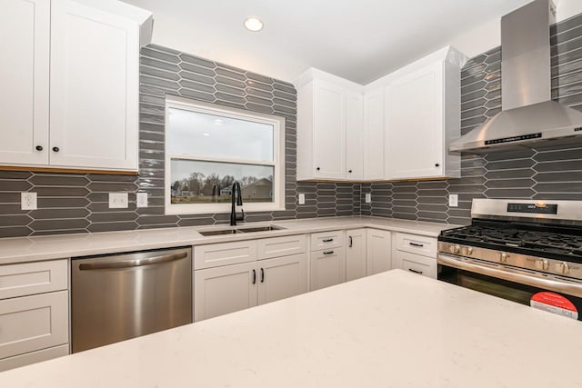 kitchen featuring backsplash, stainless steel appliances, sink, wall chimney range hood, and white cabinets