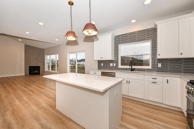 kitchen with white cabinets, a large fireplace, and hanging light fixtures