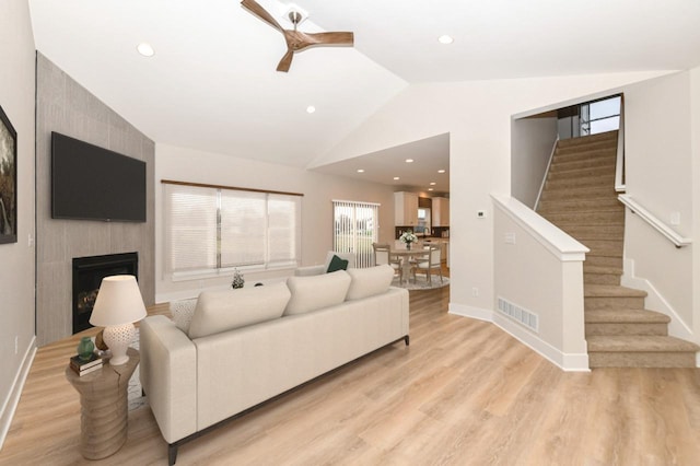 1411 Tamarack St, Delavan, WI 53115 - living room featuring a ceiling fan, stairway, vaulted ceiling, light wood-style flooring, and a large fireplace