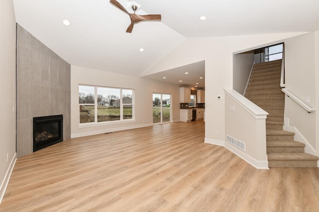 1411 Tamarack St, Delavan, WI 53115 - unfurnished living room featuring light wood finished floors, stairway, ceiling fan, a large fireplace, and recessed lighting