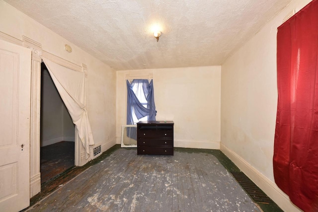 bonus room with dark wood-type flooring and a textured ceiling