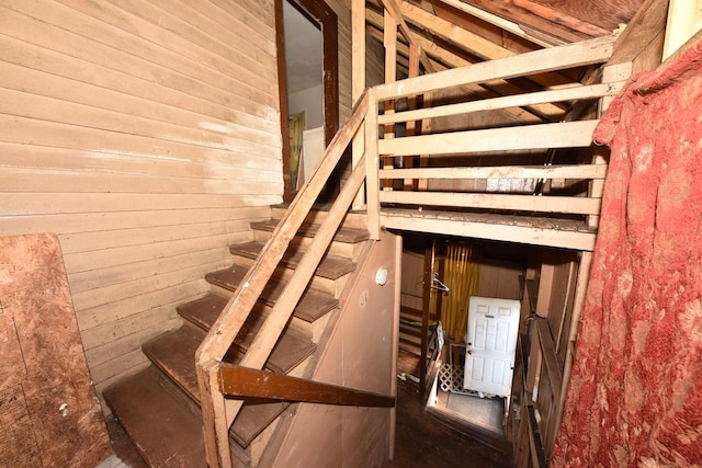 staircase featuring wood walls