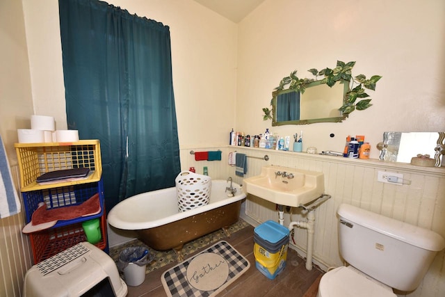 bathroom with toilet, a tub, and hardwood / wood-style flooring