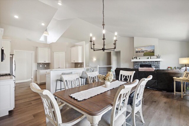7759 Sunstone Ct, De Pere, WI 54115 - dining space featuring a chandelier, dark wood finished floors, a fireplace, and high vaulted ceiling