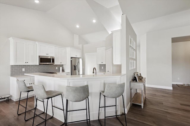 7759 Sunstone Ct, De Pere, WI 54115 - kitchen featuring appliances with stainless steel finishes, a kitchen bar, white cabinets, a peninsula, and high vaulted ceiling