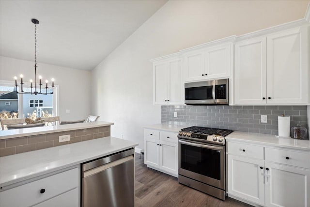 7759 Sunstone Ct, De Pere, WI 54115 - kitchen with stainless steel appliances, vaulted ceiling, a chandelier, backsplash, and dark wood-style flooring