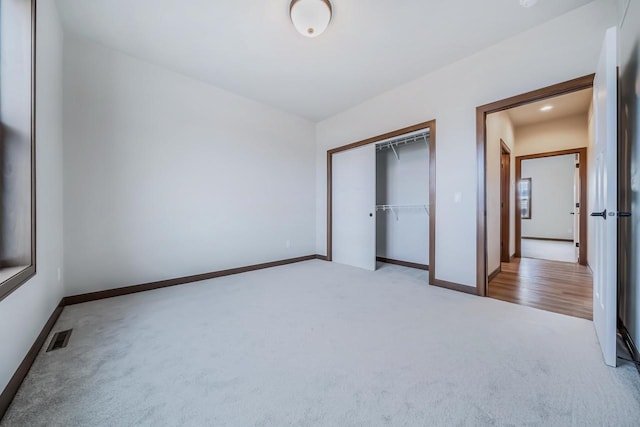 unfurnished bedroom featuring a closet and light colored carpet