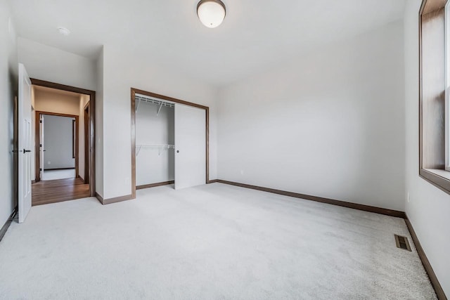 unfurnished bedroom with a closet and light colored carpet