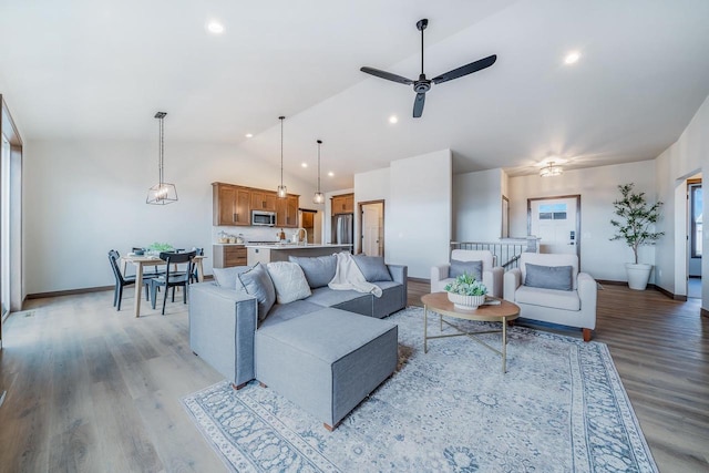 living room featuring ceiling fan, lofted ceiling, and light wood-type flooring