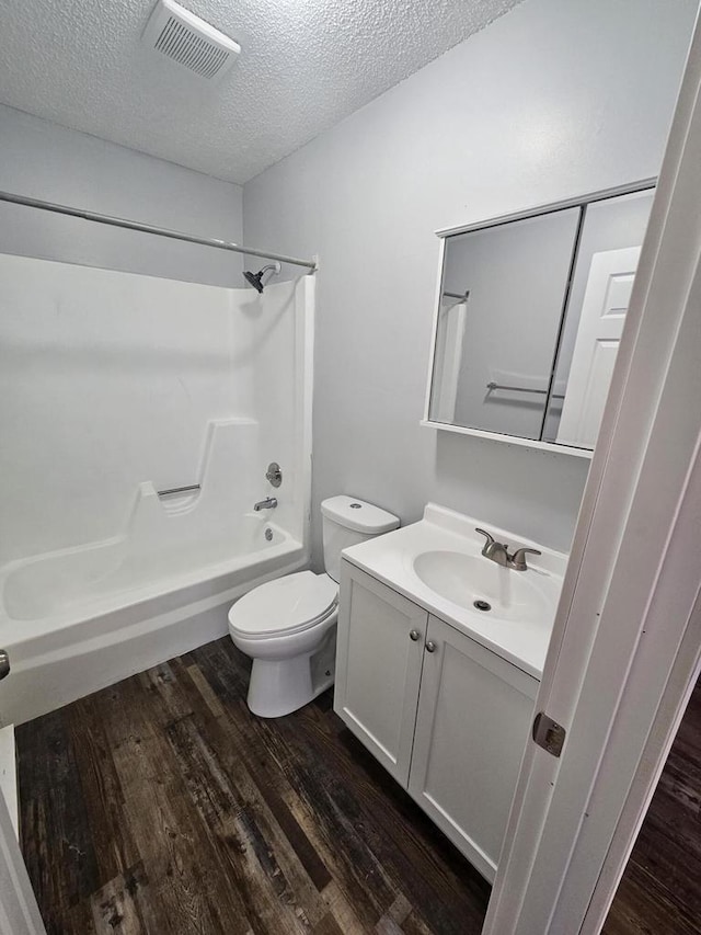 full bathroom featuring hardwood / wood-style floors, vanity, toilet, a textured ceiling, and shower / bath combination