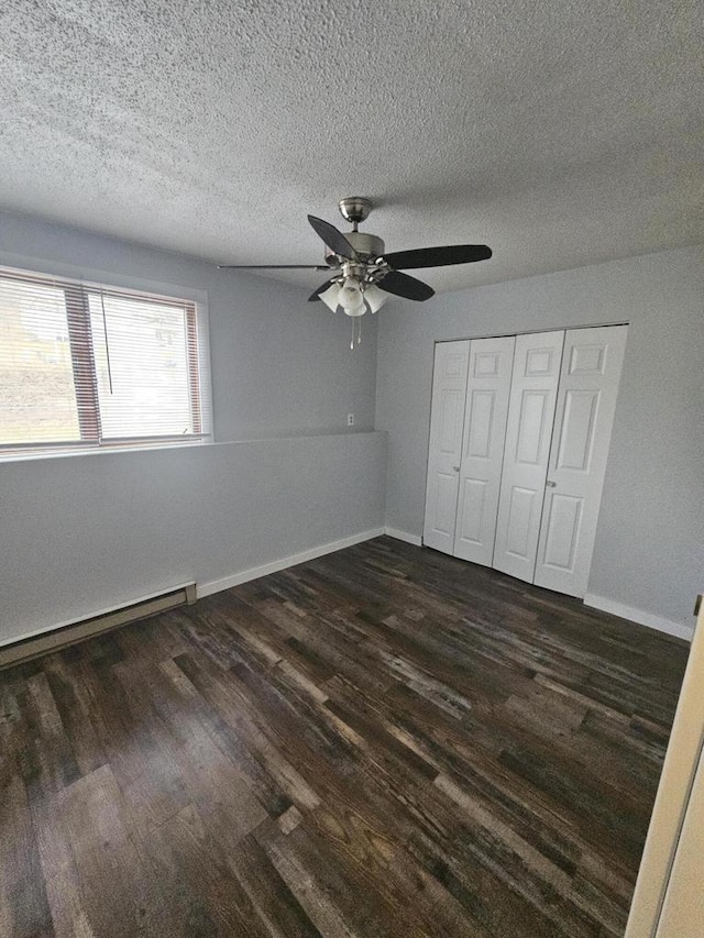 unfurnished bedroom featuring a textured ceiling, baseboard heating, ceiling fan, dark hardwood / wood-style floors, and a closet