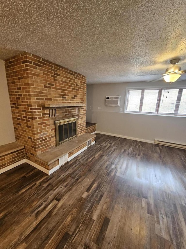 unfurnished living room featuring dark wood-type flooring, a baseboard heating unit, a textured ceiling, a fireplace, and a wall mounted AC