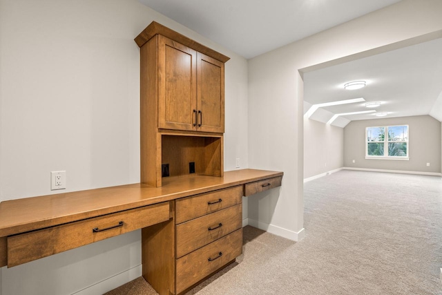 office with lofted ceiling, built in desk, and light carpet