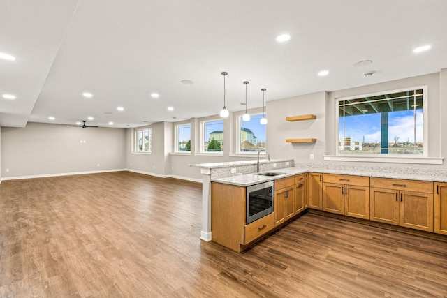 kitchen with kitchen peninsula, pendant lighting, sink, and hardwood / wood-style floors