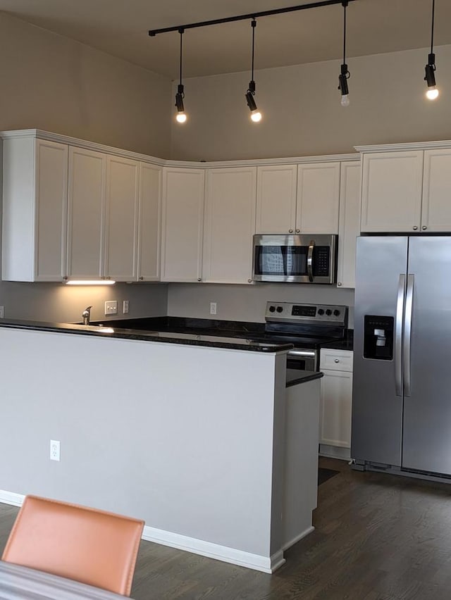 kitchen featuring dark wood-type flooring, white cabinetry, pendant lighting, and stainless steel appliances