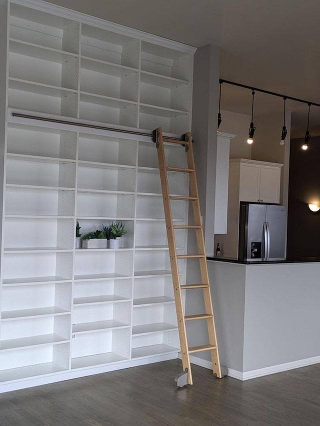 stairs with built in shelves, wood-type flooring, and rail lighting