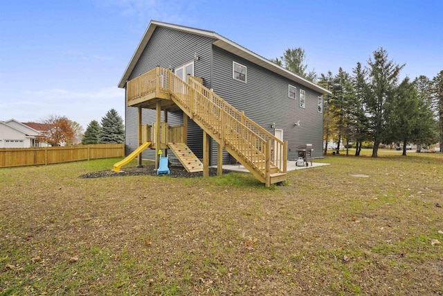 back of house featuring a yard and a playground