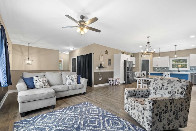 living room featuring ceiling fan with notable chandelier, hardwood / wood-style flooring, and sink